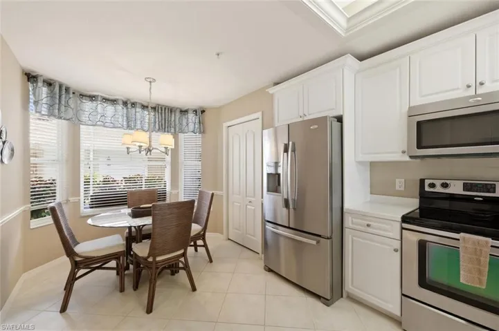 Kitchen featuring stainless steel appliances, white cabinets, light countertops, light tile patterned floors, and a chandelier