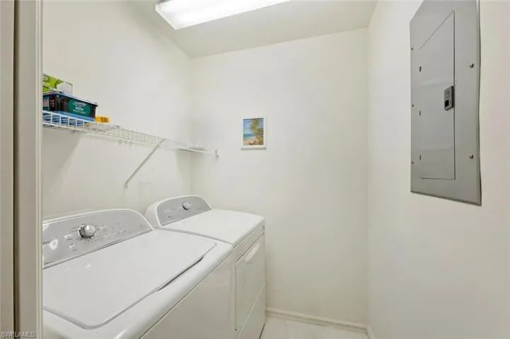 Laundry room with electric panel and washing machine and clothes dryer