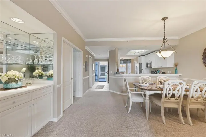 Dining area with ornamental molding and light carpet