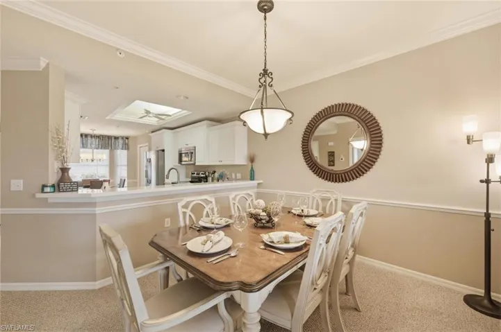 Dining area featuring light colored carpet, crown molding, and a skylight