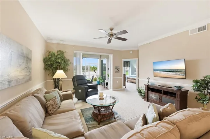 Living room featuring carpet flooring, crown molding, and a ceiling fan