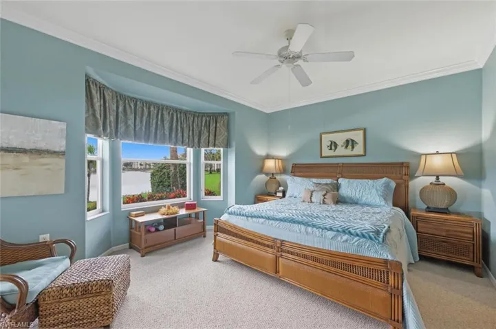 Bedroom with ornamental molding, light carpet, and a ceiling fan