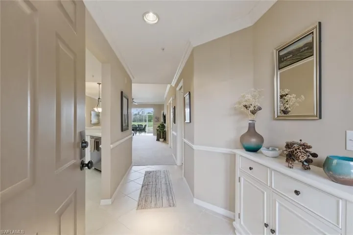 Hall featuring crown molding, light carpet, and light tile patterned flooring