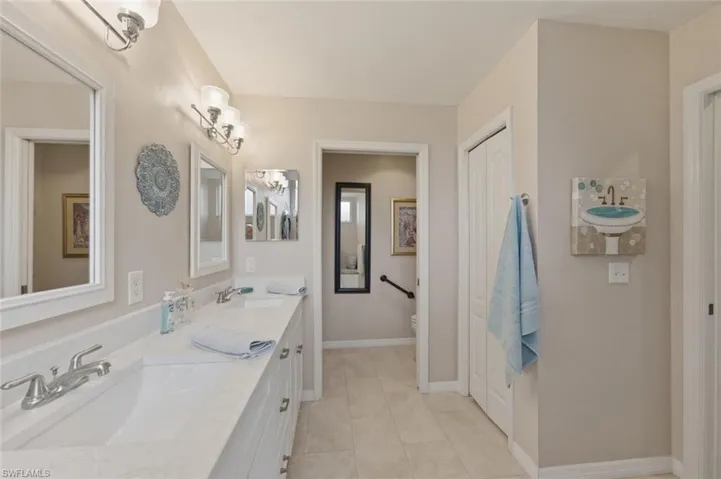 Bathroom featuring double vanity, light tile patterned floors, and a closet