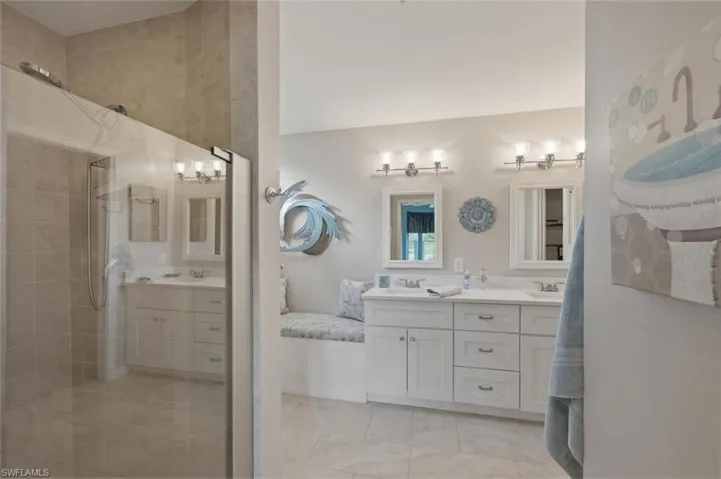 Bathroom featuring double vanity, a tile shower, and light tile patterned flooring