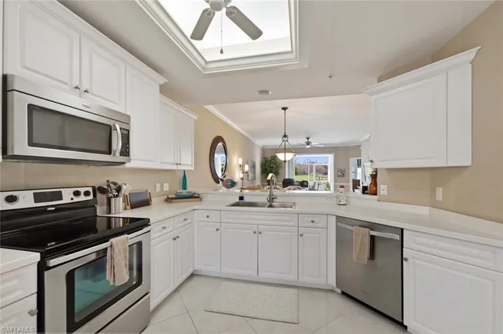 Kitchen featuring ceiling fan, stainless steel appliances, crown molding, white cabinetry, and light countertops