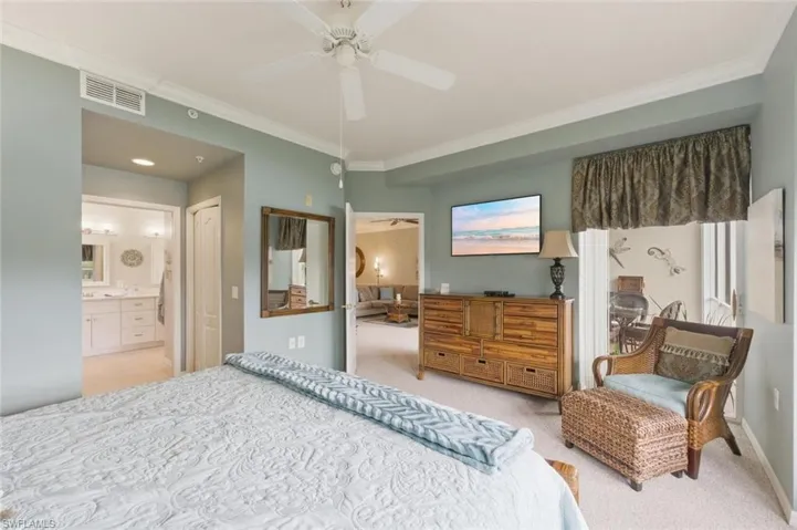 Bedroom with crown molding, light carpet, a ceiling fan, and ensuite bathroom