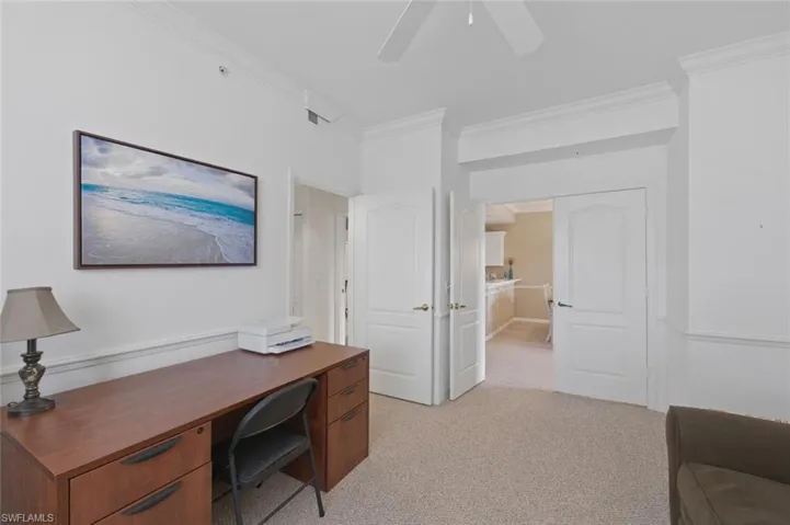 Office space featuring light colored carpet, ornamental molding, and a ceiling fan