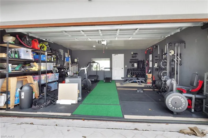 View of 2 car garage with storage and negotiable gym equipment