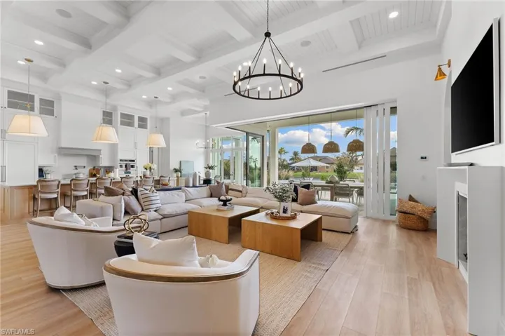 Living room featuring coffered ceiling, light wood-type flooring, a fireplace, and hanging lights