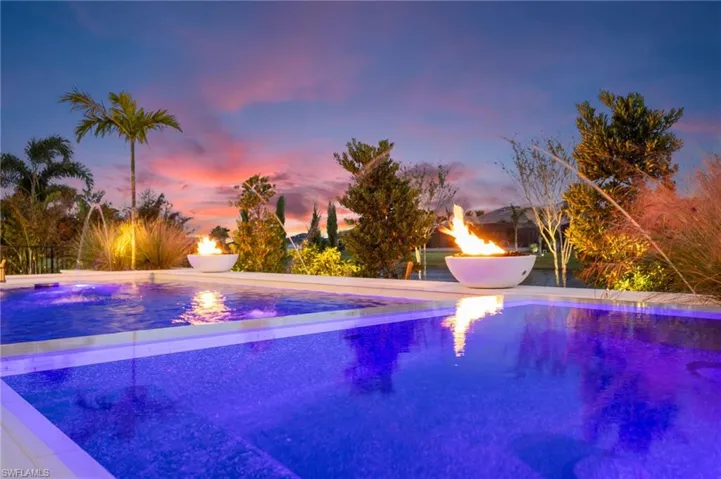 Pool at dusk featuring an outdoor pool, an outdoor fire pit, and a patio