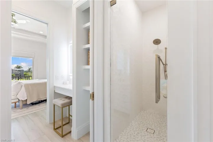 Ensuite bathroom featuring a walk in shower, built in shelves, and light wood finished floors