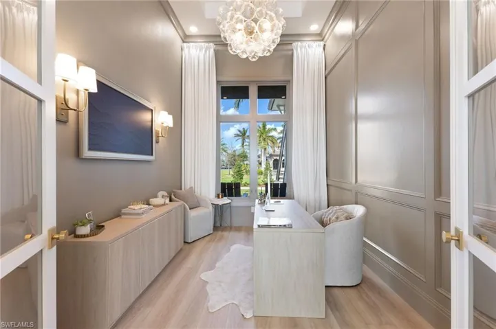 Sitting room featuring hanging lights, a decorative wall, light wood-style floors, and crown molding