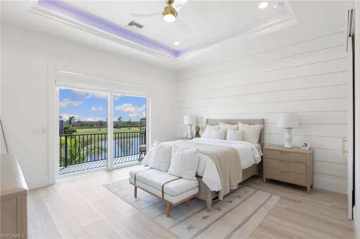 Bedroom with a tray ceiling, light wood finished floors, a ceiling fan, access to exterior, and recessed lighting