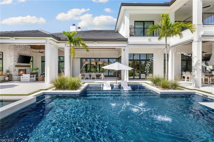 Back of property with a patio area, outdoor dining area, an outdoor pool, a balcony, and a chimney