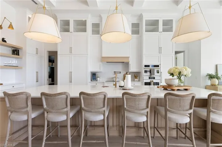 Kitchen with pendant lighting, white cabinets, and glass insert cabinets