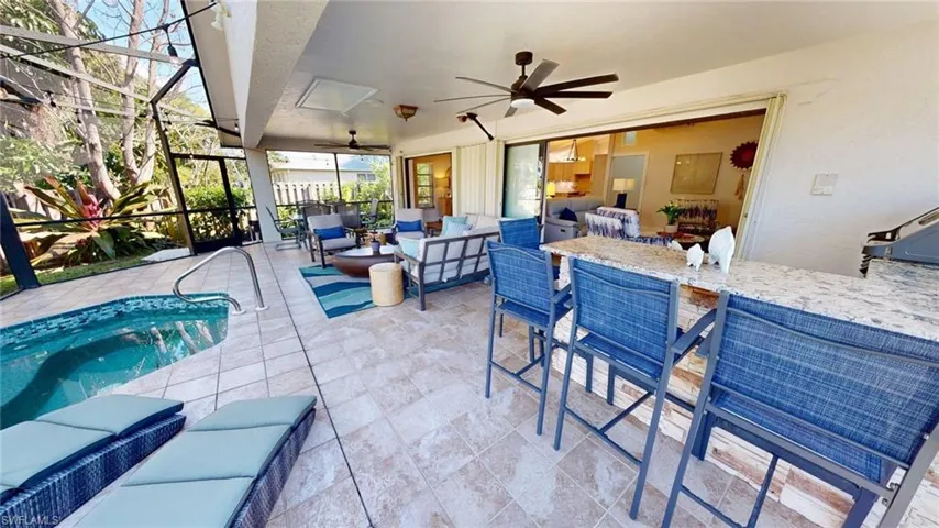 View of lanai featuring plunge pool/hot tub, 2 sun loungers, 6 person dining table, gas grill, raised bar, wine fridge