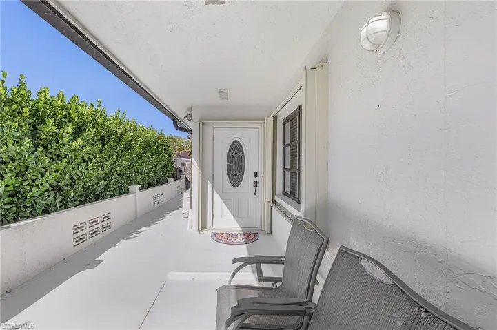 Covered porch entrance to property featuring a double glider, and 2 chairs to enjoy beautiful sunsets