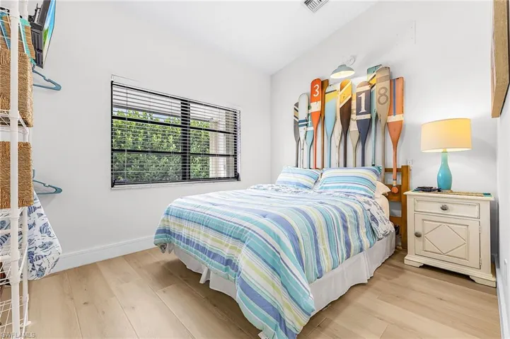 Nautical vaulted bedroom featuring a Queen bed, double window overlooking covered entry porch, TV, ceiling fan and ample open closet hanging concept