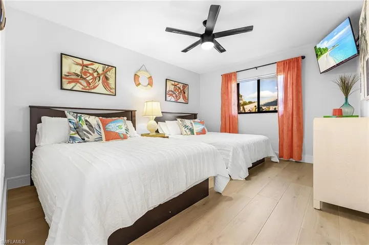 Bedroom featuring 2 Queen beds, double window overlooking lush flower garden, TV and a ceiling fan