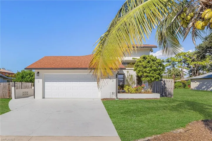 View of front of house with concrete driveway driveway, stucco siding, an attached 2 car garage and coconut tree