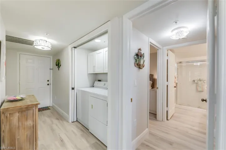 Laundry area featuring light wood-style flooring, cabinet space, and separate washer and dryer