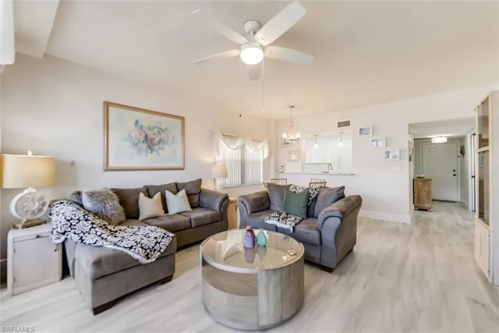 Living room with wood finished floors, ceiling fan, and a chandelier