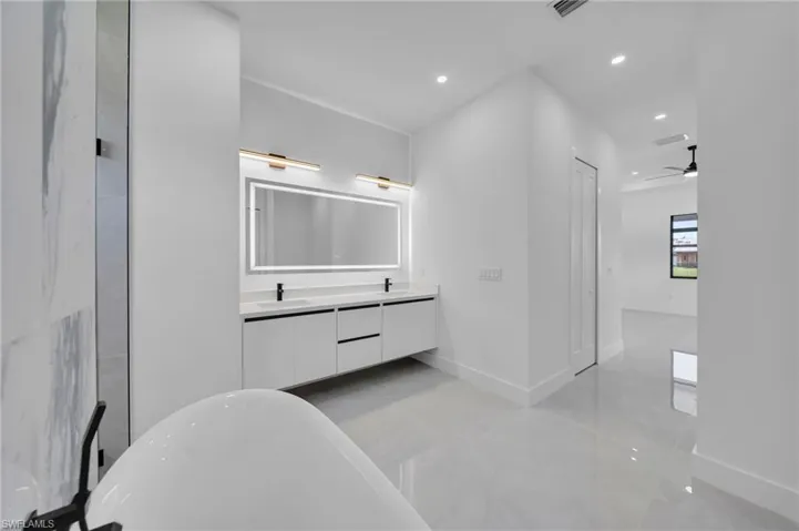 Full bathroom featuring a freestanding tub, double vanity, recessed lighting, and a ceiling fan