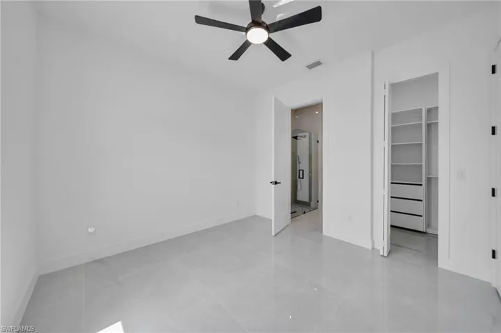 Unfurnished bedroom with a walk in closet, ceiling fan, and a closet
