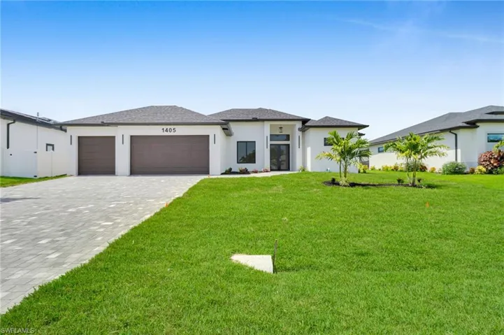 Prairie-style house featuring a garage, stucco siding, decorative driveway, and a front yard