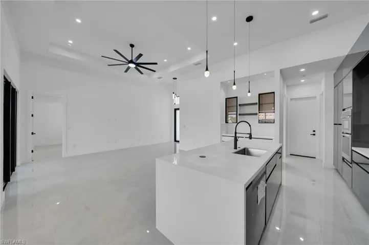 Kitchen featuring modern cabinets, a raised ceiling, stainless steel appliances, recessed lighting, and a spacious island