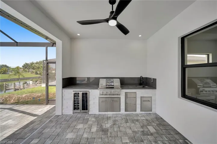 View of patio / terrace with an outdoor kitchen, wine cooler, glass enclosure, and ceiling fan