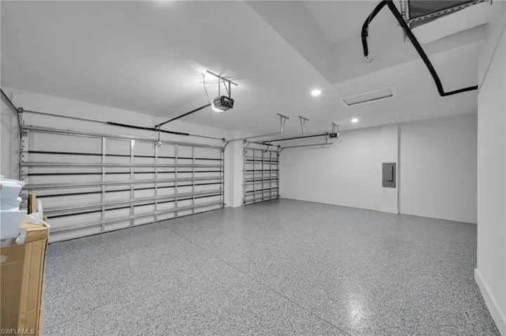 Garage featuring a garage door opener, electric panel, and recessed lighting