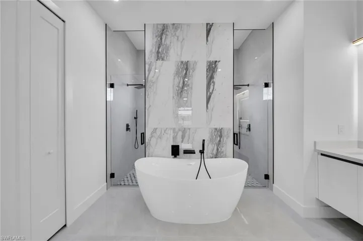 Bathroom featuring a shower stall, a soaking tub, and vanity
