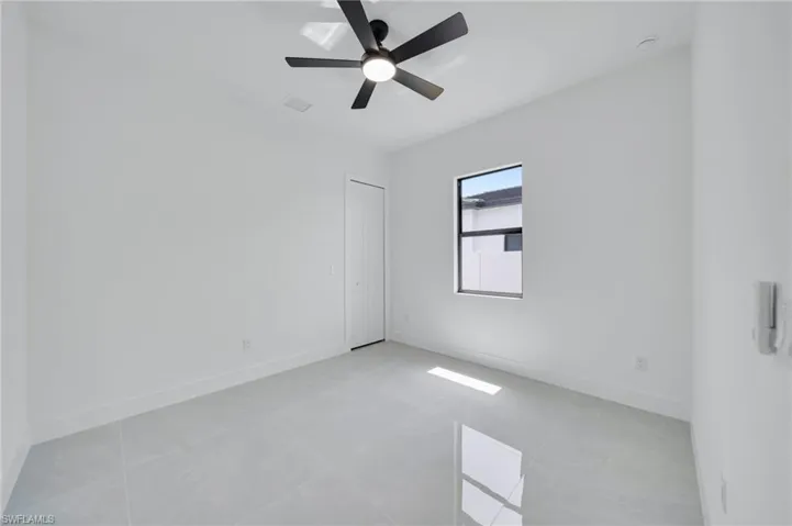 Unfurnished room with ceiling fan and light tile patterned floors