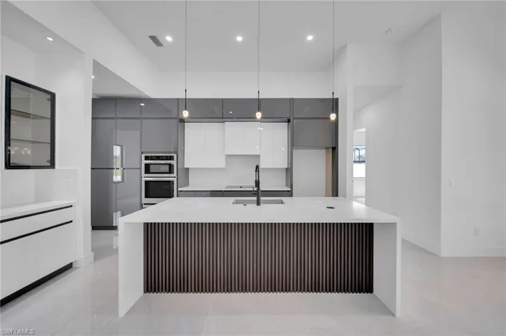 Kitchen featuring modern cabinets, gray cabinets, light countertops, a spacious island, and recessed lighting