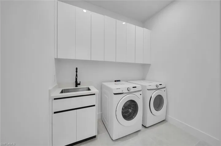Washroom with cabinet space and washer and clothes dryer