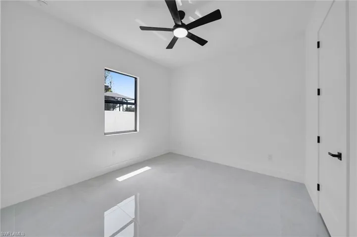 Empty room featuring a ceiling fan and light tile patterned flooring