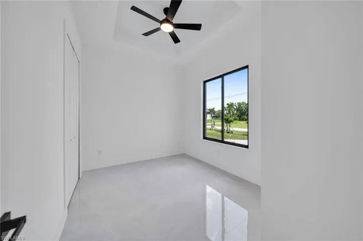 Empty room featuring a tray ceiling and ceiling fan