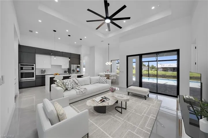 Living area featuring a high ceiling, recessed lighting, a raised ceiling, a ceiling fan, and a chandelier