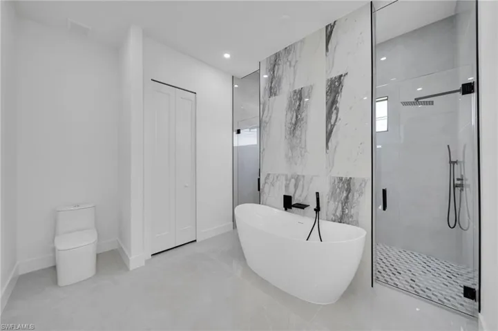 Full bath with a soaking tub, a shower stall, recessed lighting, and tile walls