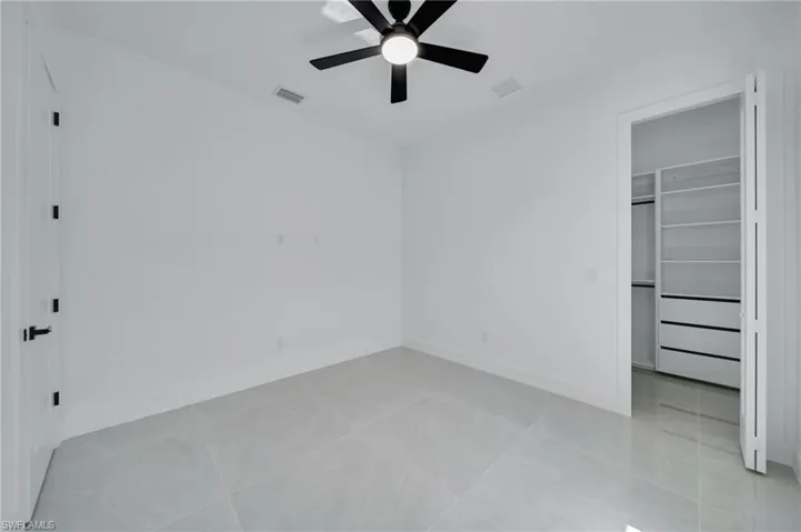 Unfurnished bedroom with a walk in closet, a closet, and ceiling fan