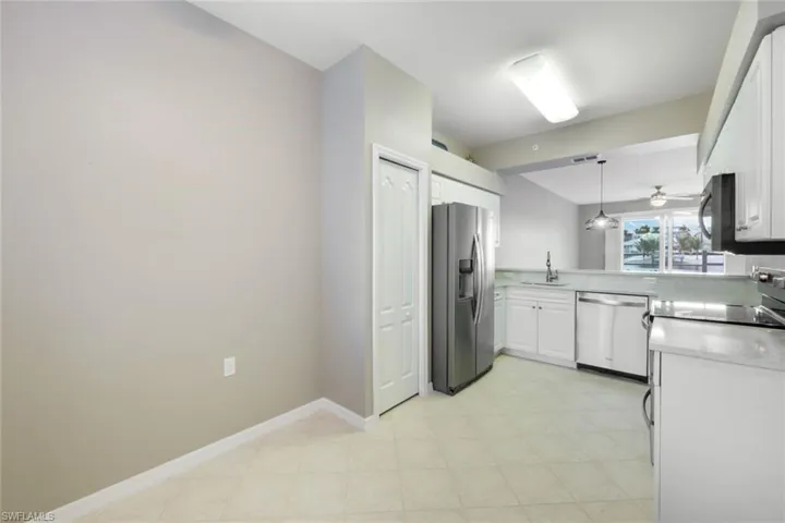 Kitchen with kitchen peninsula, stainless steel appliances, hanging light fixtures, white cabinets, and sink