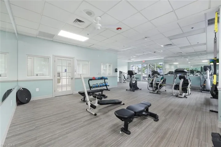 Workout area featuring light carpet, ceiling fan, and a drop ceiling