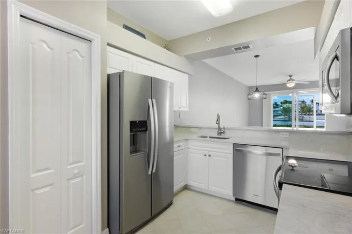 Kitchen with pendant lighting, white cabinetry, stainless steel appliances, sink, and ceiling fan