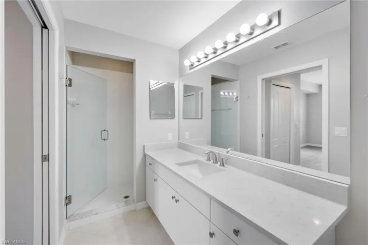 Bathroom with an enclosed shower, vanity, and tile patterned flooring
