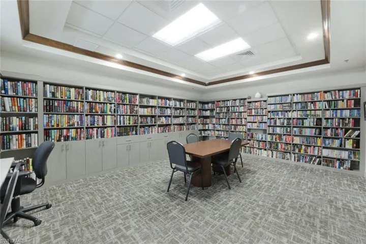 Carpeted office space featuring a raised ceiling and crown molding