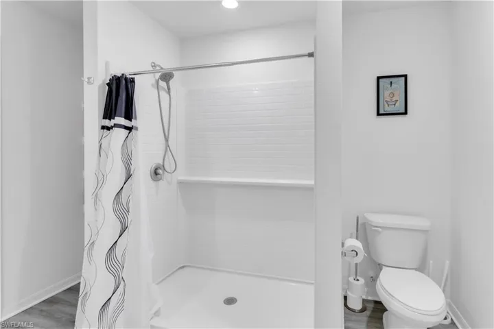 Bathroom featuring toilet, a shower with shower curtain, and hardwood / wood-style flooring