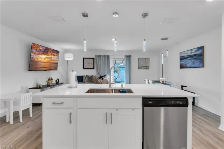 Kitchen featuring sink, dishwasher, white cabinets, and light wood-type flooring