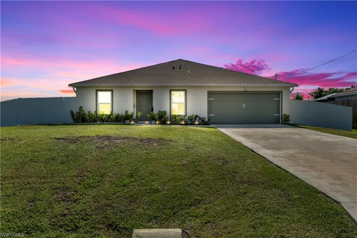 View of front facade featuring a yard and a garage